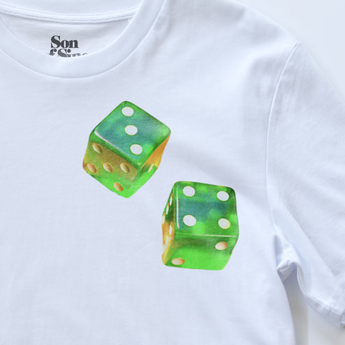 White electronic music T-shirt with a printed graphic of two green translucent dice on the chest. The inside collar shows the brand name 'Son of Sine'.