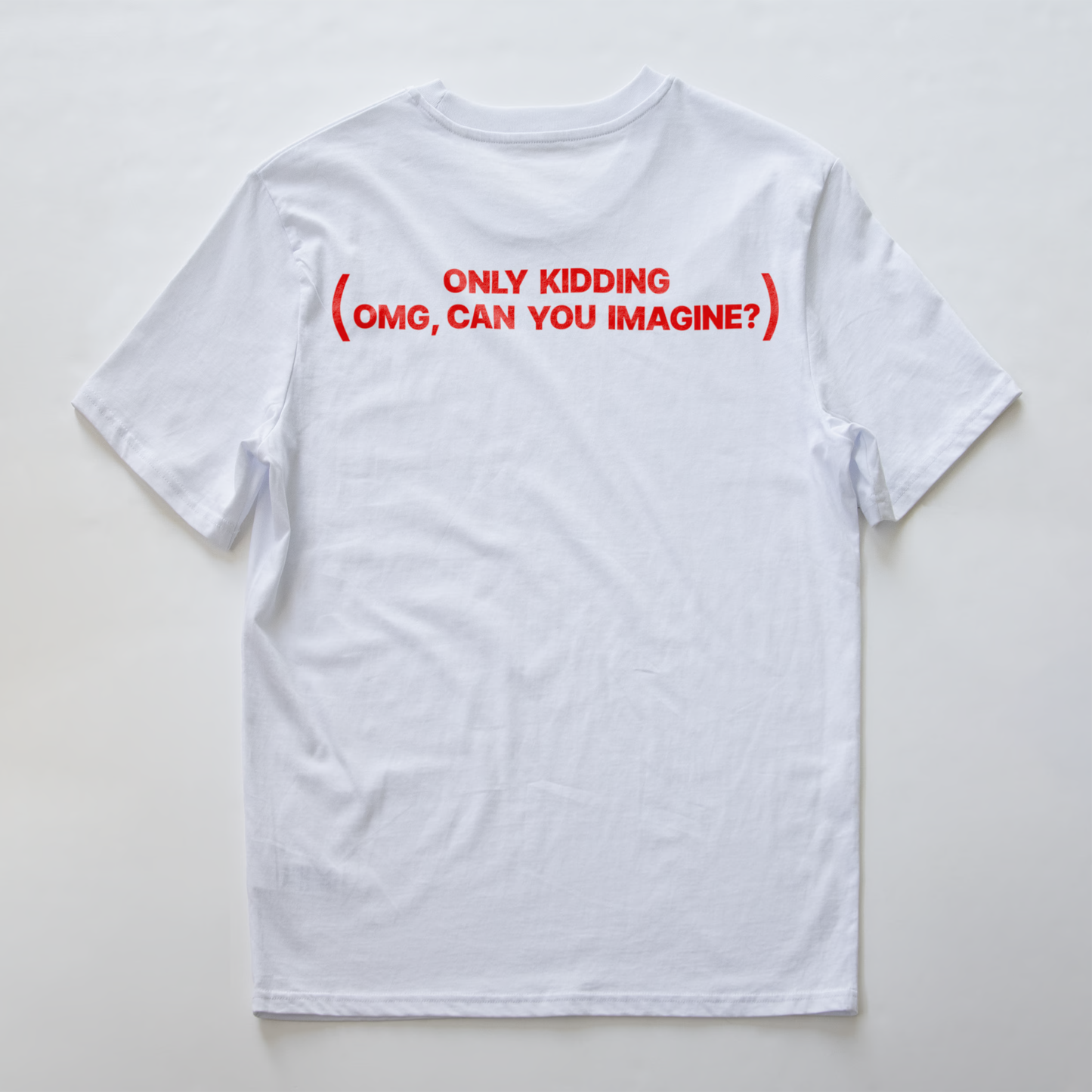 A white short-sleeve electronic music t-shirt shown from the back, featuring the red text 'ONLY KIDDING (OMG, CAN YOU IMAGINE?)' printed across the upper back.