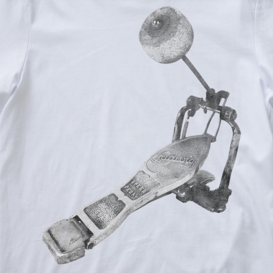 A close-up of a white fabric surface featuring a large grayscale printed graphic of a metal drum pedal.