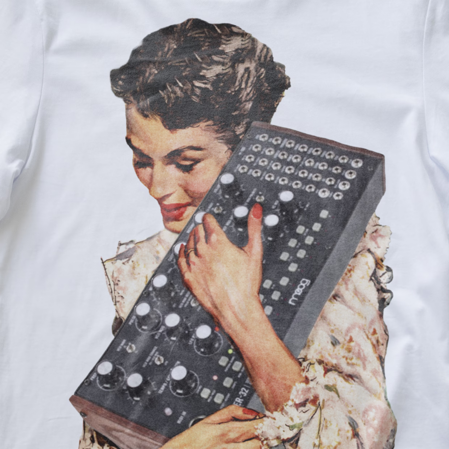 A close-up of a synth t-shirt a large vintage-style graphic print of a woman holding a dark gray modular synthesizer mother 32.