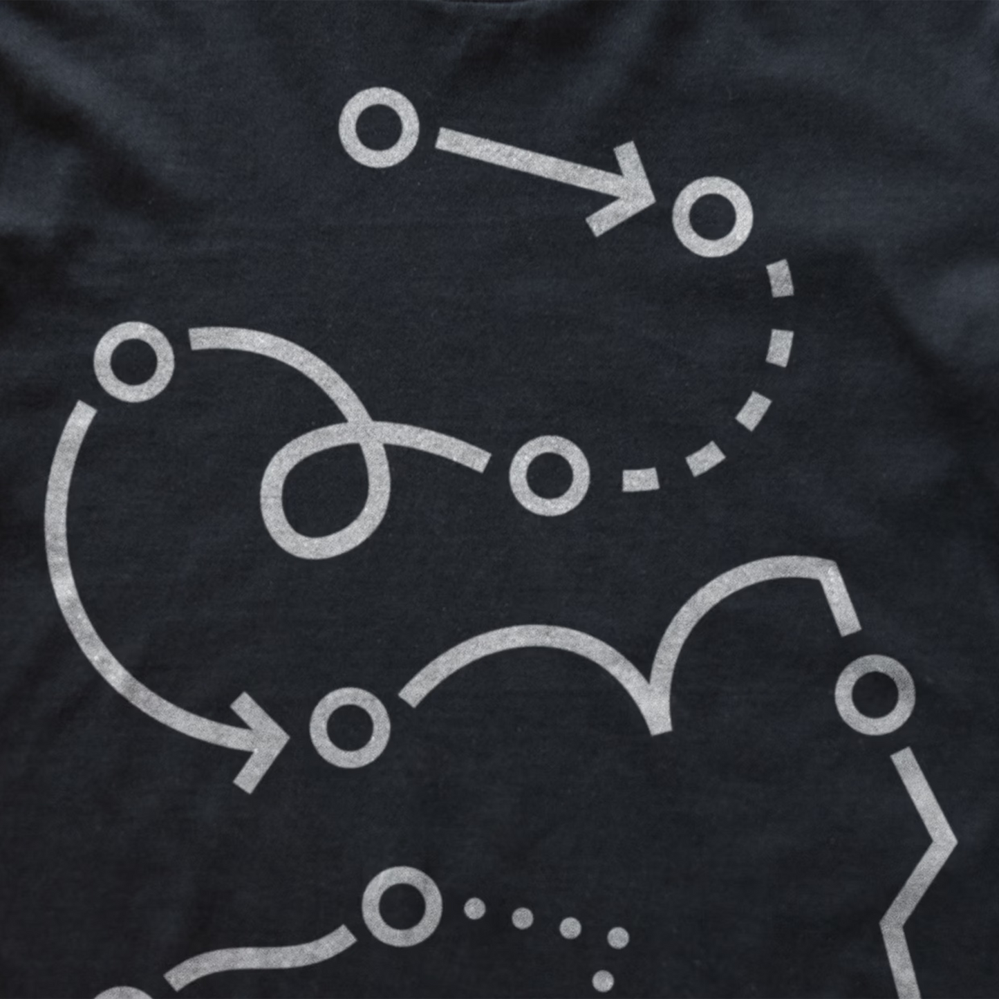 Close-up of a dark charcoal gray modular synth t-shirt featuring a white graphic print of abstract flowing lines, arrows, and circular nodes.