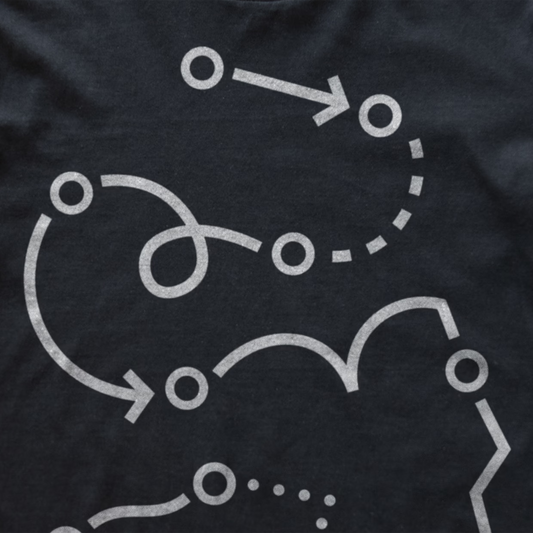 Close-up of a dark charcoal gray modular synth t-shirt featuring a white graphic print of abstract flowing lines, arrows, and circular nodes.