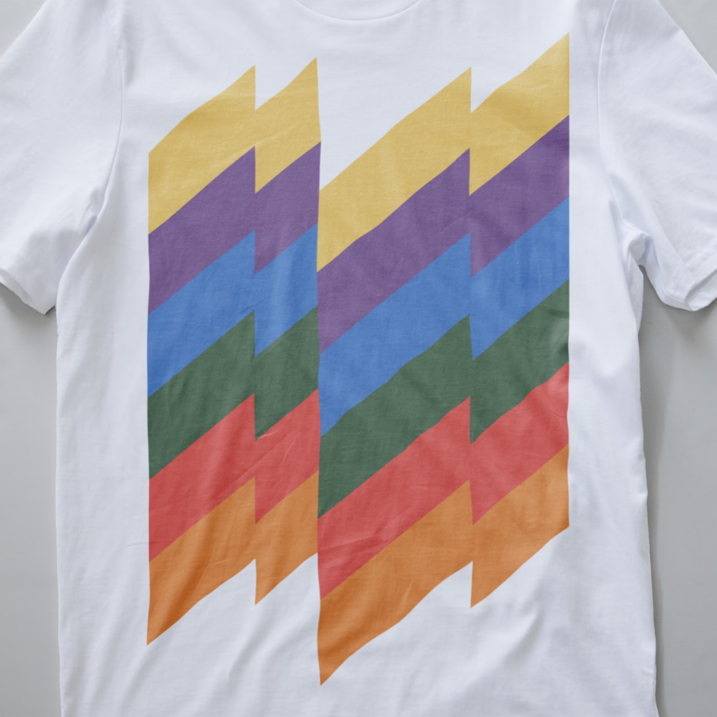 A close up of a white modular synth t-shirt with a retro graphic print of vertical zigzag stripes in yellow, purple, blue, green, red, and orange.