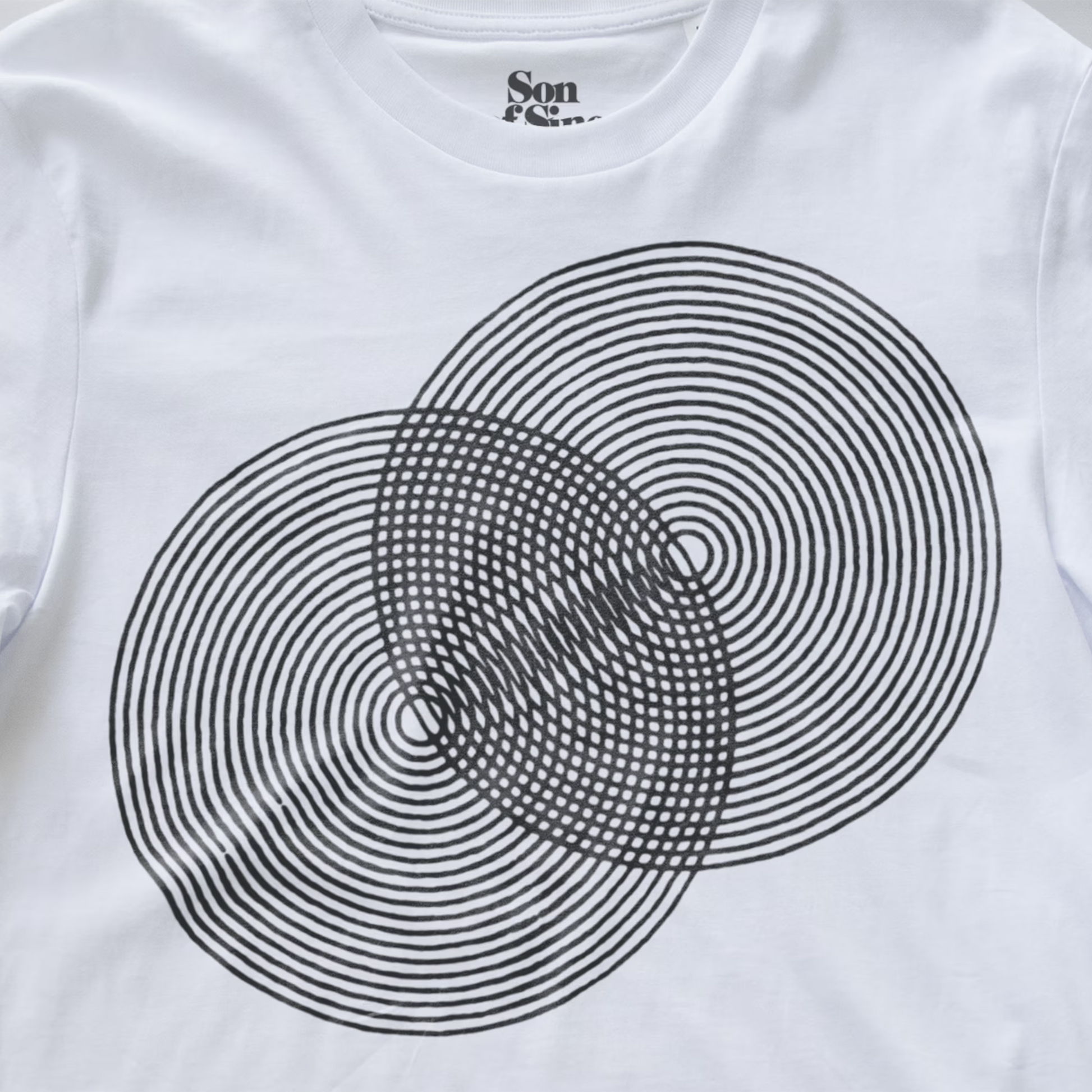 White modular synth t-shirt featuring a black concentric circle optical illusion graphic on the front, with the brand name 'Son of Sine' printed inside the collar.
