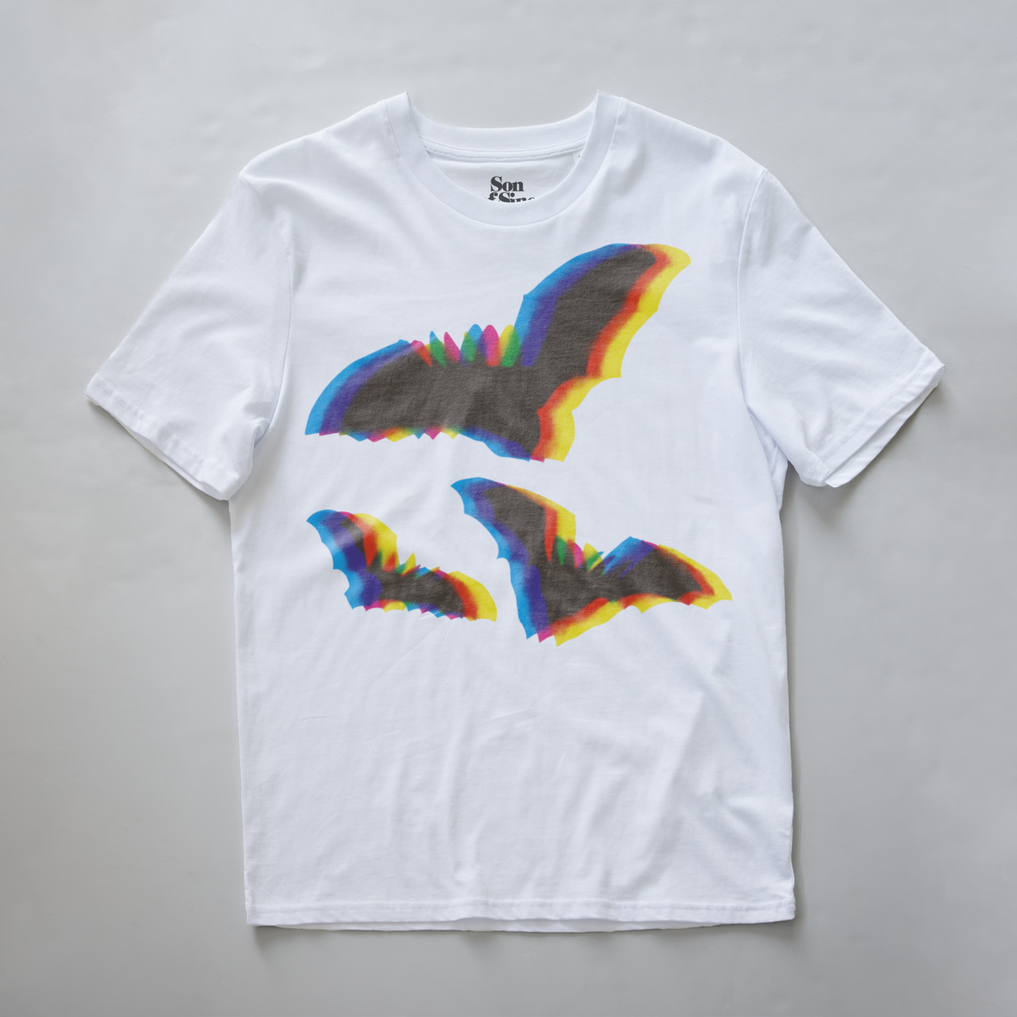 An electronic music t-shirt with a graphic print of two bats in the center, featuring a rainbow chromatic aberration effect.The inner neck label shows the brand 'Son of Sine'.