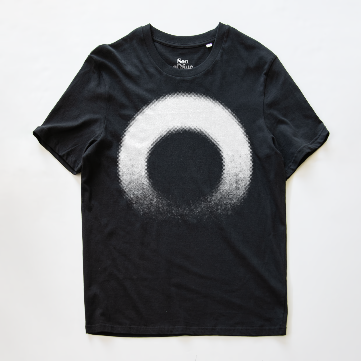 A black modular synth t-shirt with a large white circular gradient graphic on the front. The inner neck label shows the brand 'Son of Sine'.