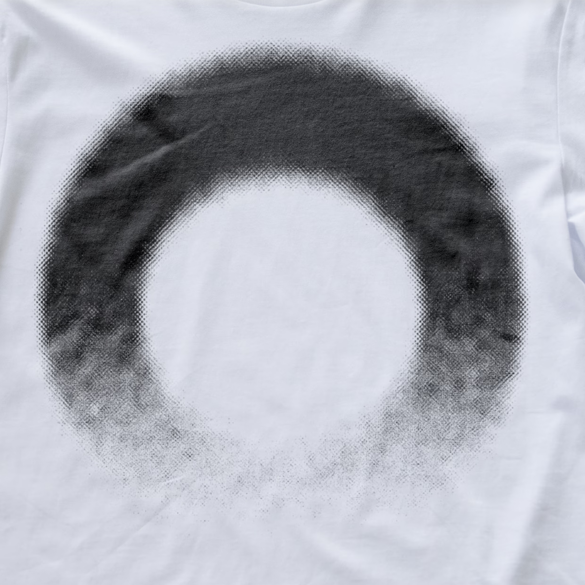 A close-up of a white modular synth t-shirt featuring a large, circular black halftone dot pattern that fades into a solid white center.