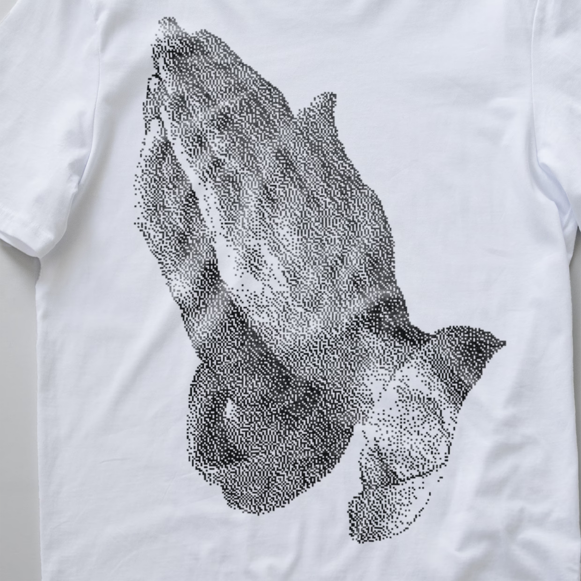 A white short-sleeve t-shirt featuring a large black bitmapped graphic of praying hands on the front.