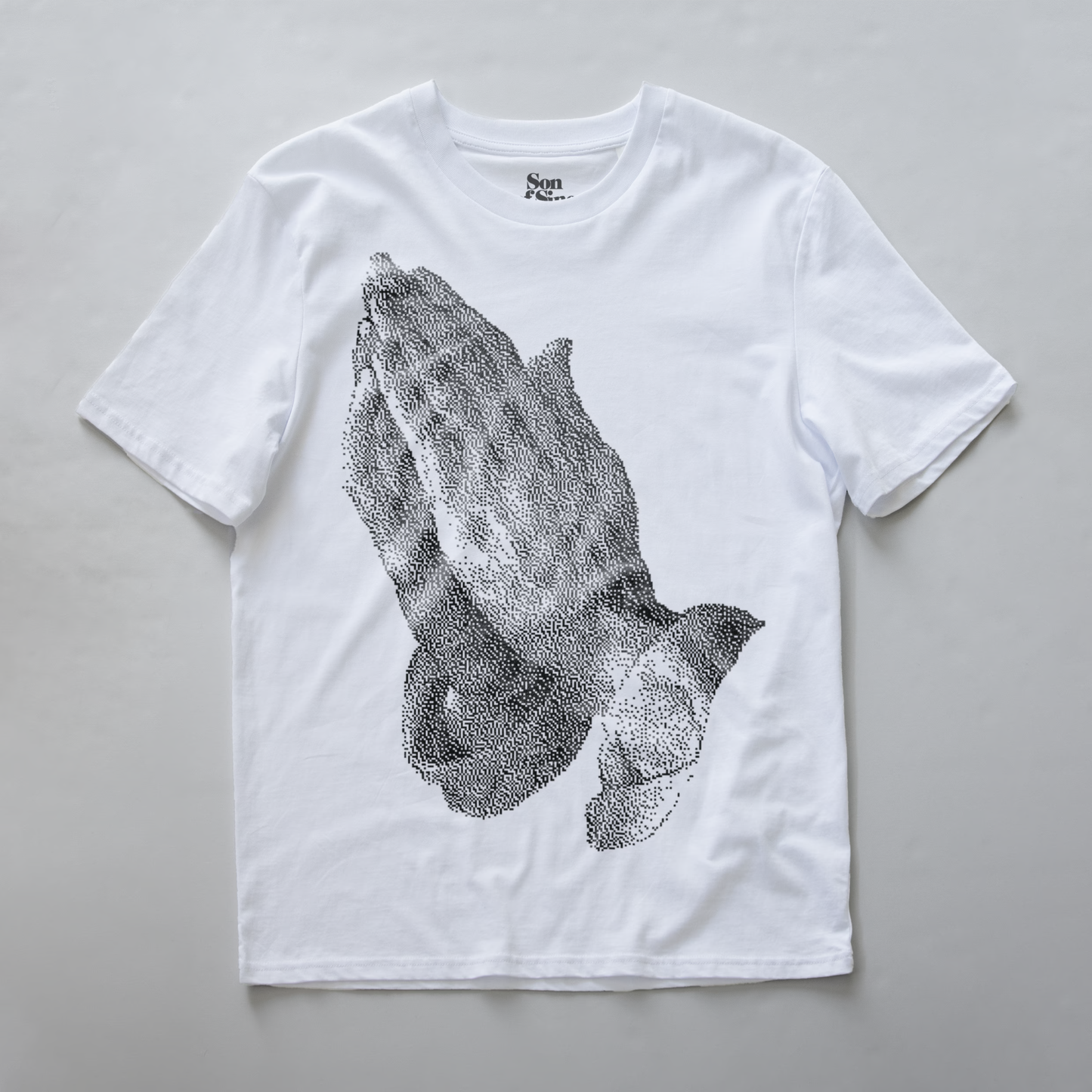 A white synth t-shirt featuring a large black digital bitmap graphic of praying hands on the front.