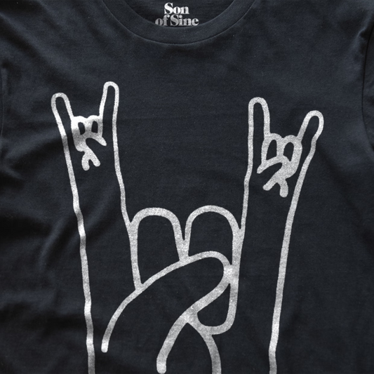 Close-up of a black music festival t-shirt featuring a white graphic of two hands making the rock on sign.