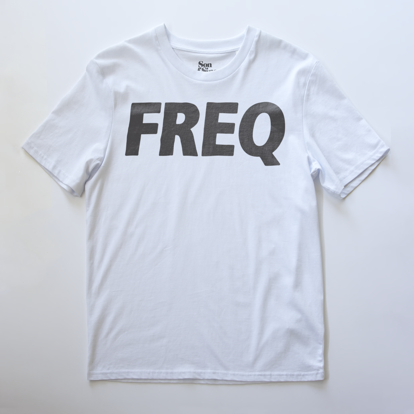 A white electronic music club wear t-shirt with the word 'FREQ' printed across the chest in large.