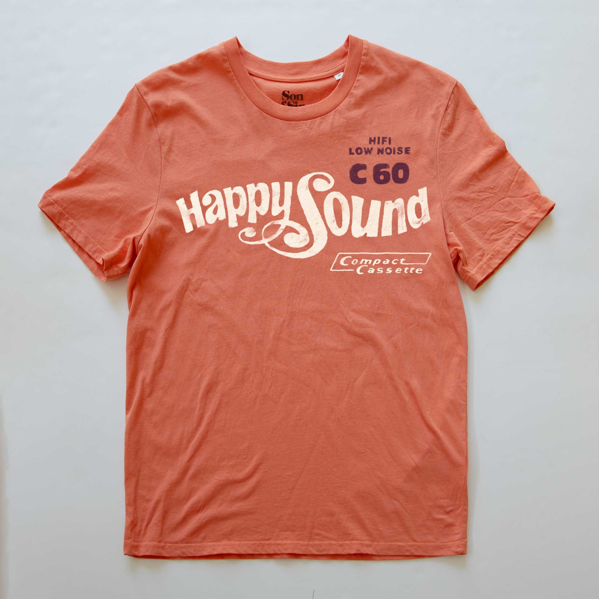 A coral orange synth-inspired T-shirt featuring the retro graphic 'Happy Sound' and 'HI-FI LOW NOISE C60 Compact Cassette' printed on the front.