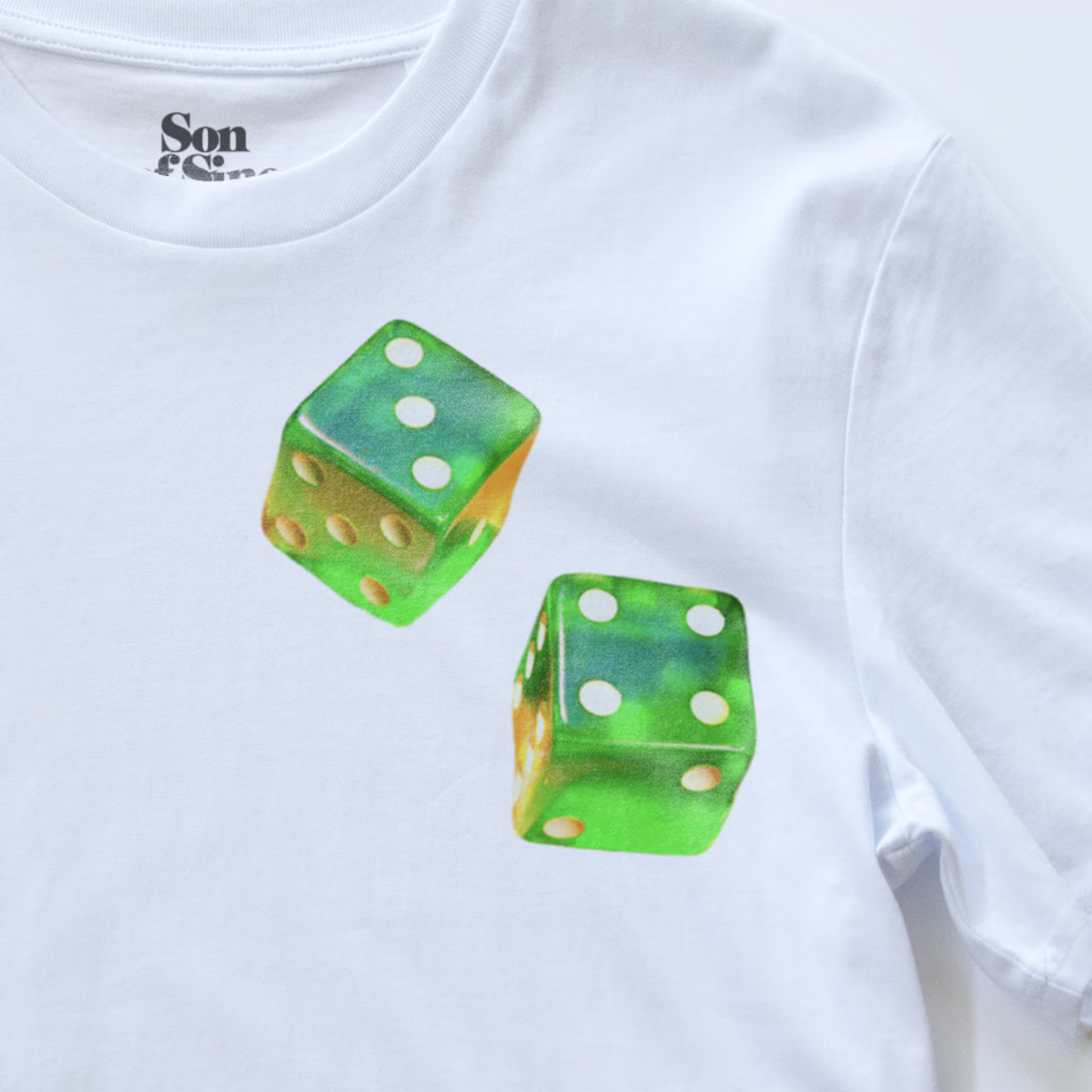 White electronic music T-shirt with a printed graphic of two green translucent dice on the chest. The inside collar shows the brand name 'Son of Sine'.