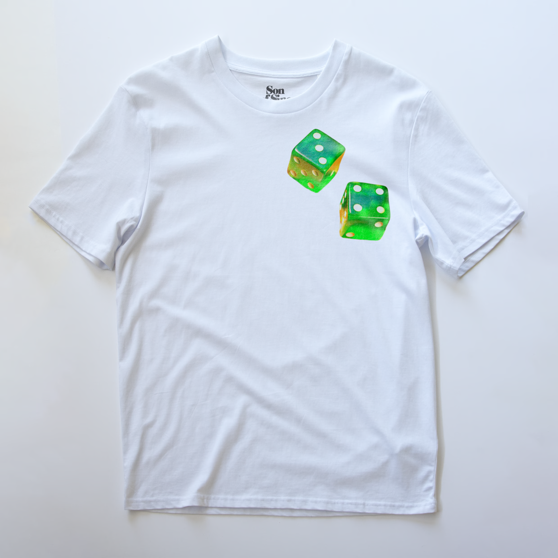A white electronic music festival t-shirt featuring two green translucent dice printed on the chest.
