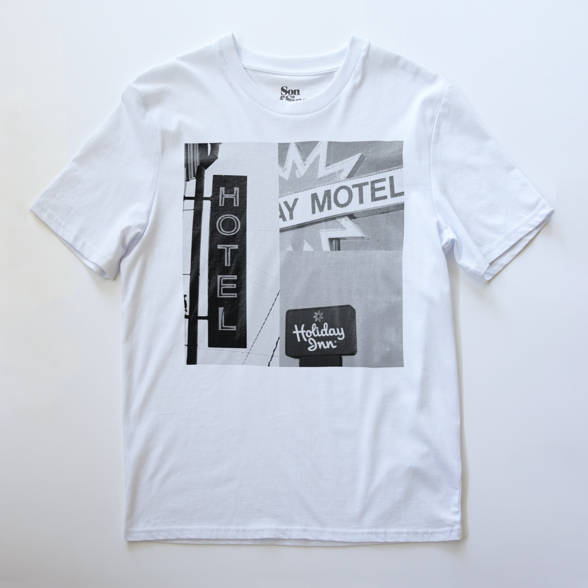 A white electronic music t-shirt with a black and white print of a vintage motel signs featuring  'Hotel', 'Motel' and 'Holiday Inn'.