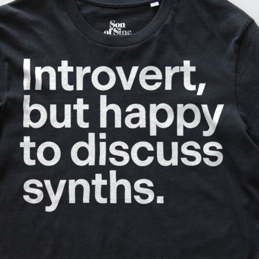 A detail image of a funny synth inspired t-shirt with bold white text reading 'Introvert, but happy to discuss synths.' printed on the front.