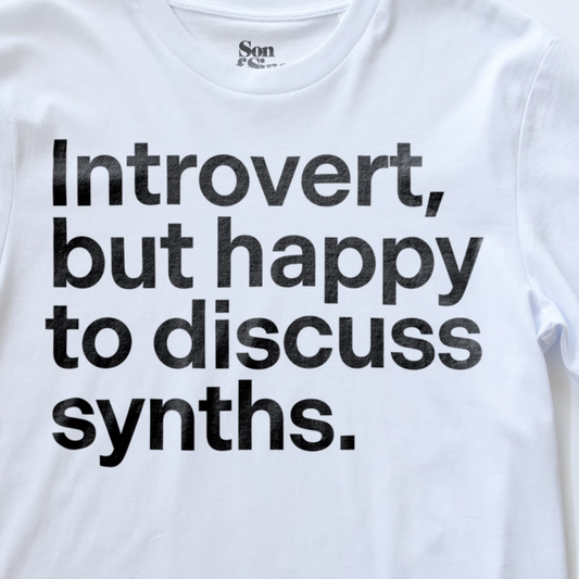 A close up of a funny synth inspired t-shirt with bold black text reading 'Introvert, but happy to discuss synths.' printed on the front.