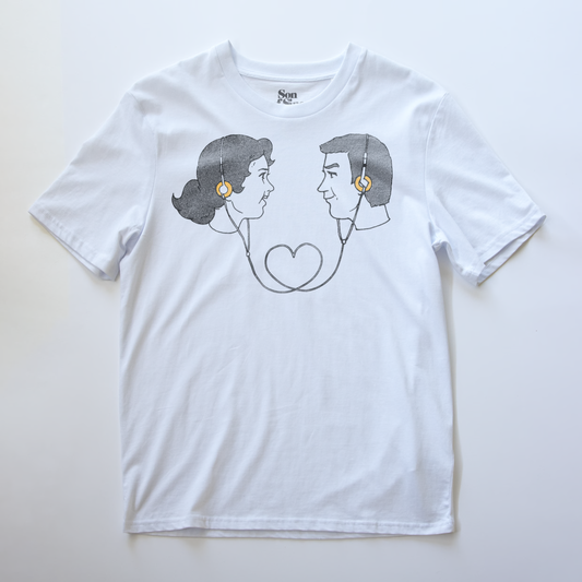 A white electronic music t-shirt with a graphic print of a retro couple facing each other wearing headphones connecting them. 