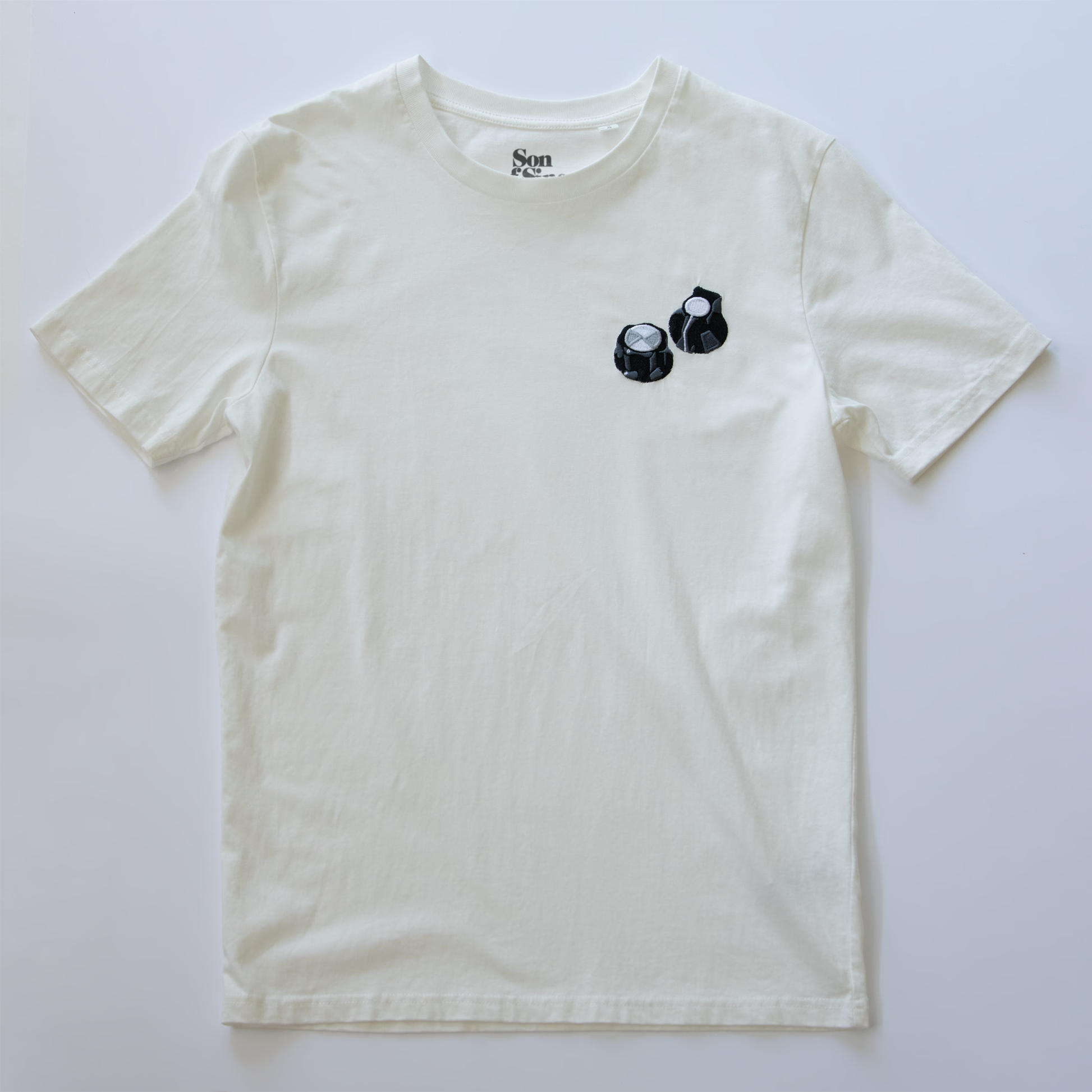 An off-white synth t-shirt with a small black graphic of two moog style controller knobs.