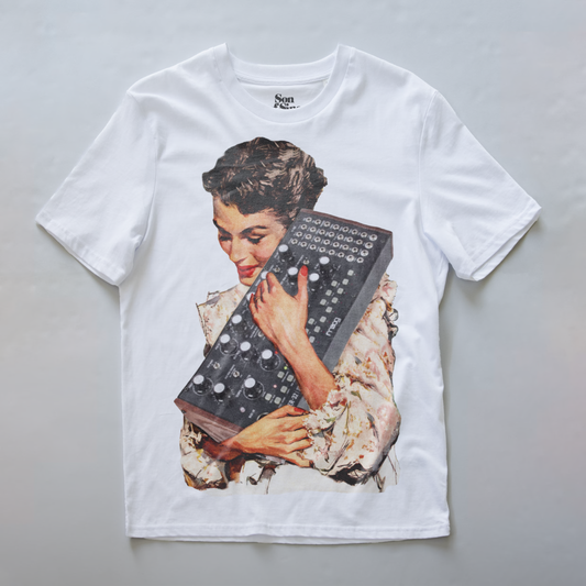 A white synth t-shirt featuring a large vintage-style graphic print of a woman holding a mother 32 modular synthesizer. 