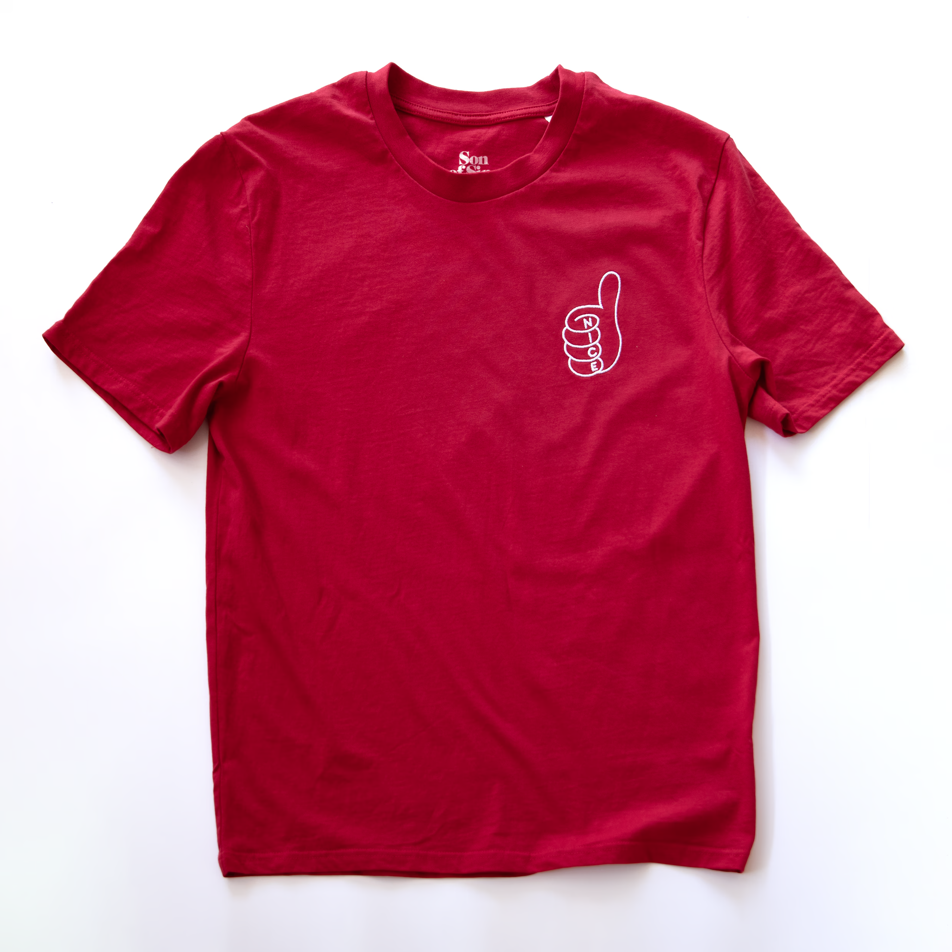 A red electronic music t-shirt with a small embroidered  line-art thumbs-up graphic on the left chest