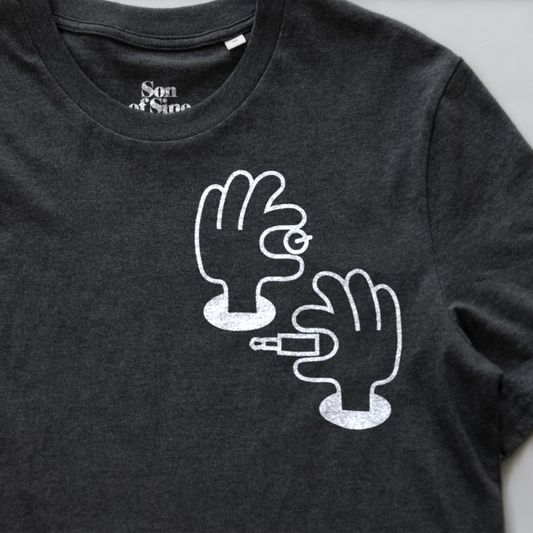 A close-up of a synth inspired t-shirt featuring a white graphic print of two illustrated hands patching and tweaking.