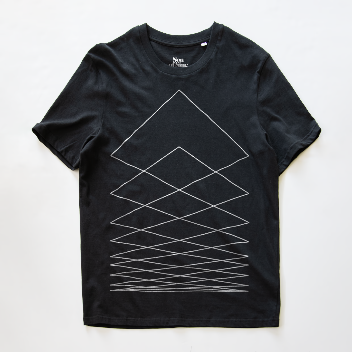 A black modular synth t-shirt with a white geometric line pattern forming nested triangles and crisscross lines on the front, laid flat against a white background. The inner collar shows the brand name 'Non.