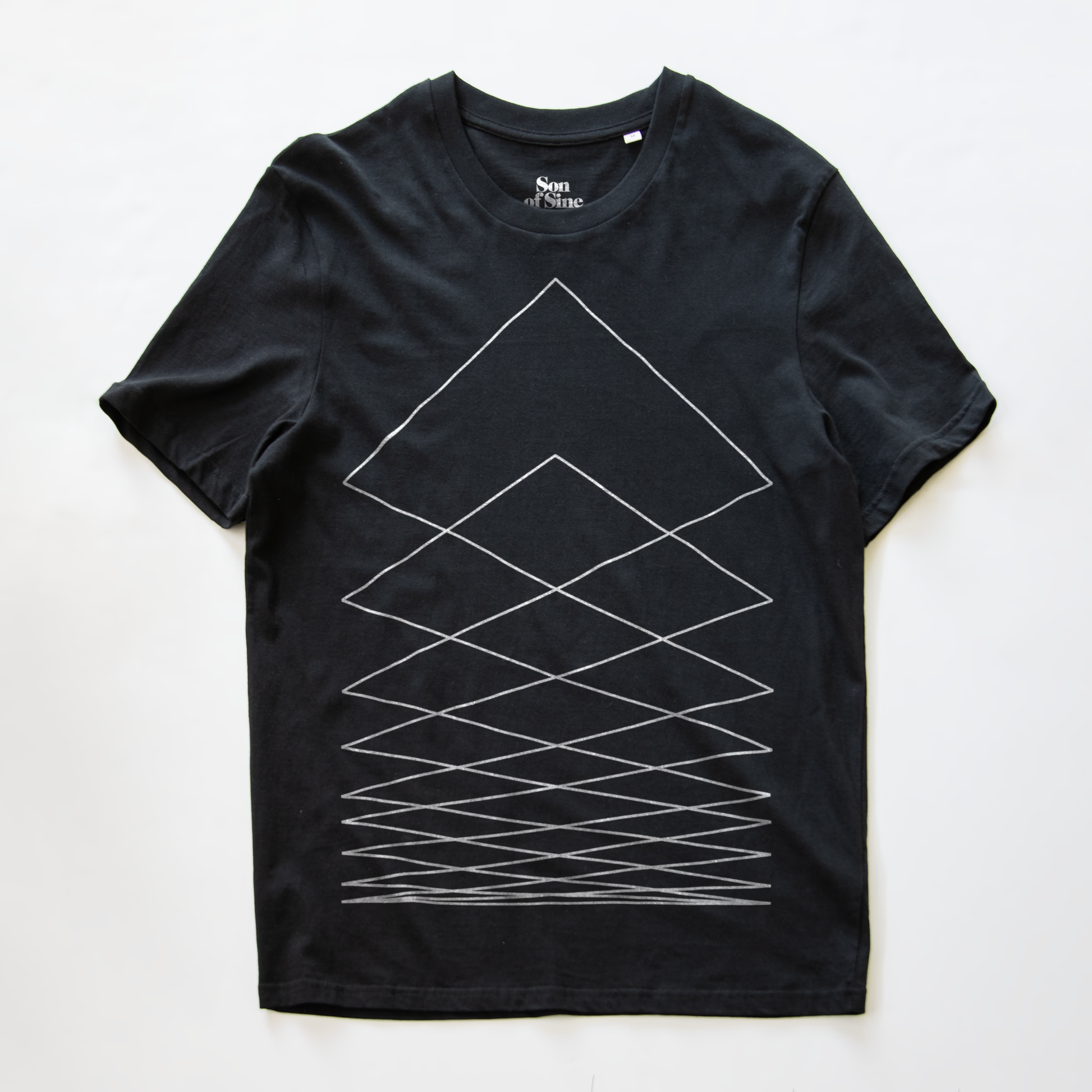 A black modular synth t-shirt with a white geometric line pattern forming nested triangles and crisscross lines on the front, laid flat against a white background. The inner collar shows the brand name 'Non.