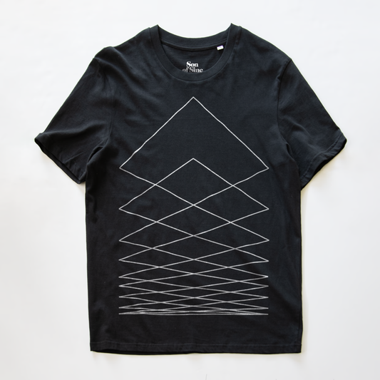 A black modular synth t-shirt with a white geometric line pattern forming nested triangles and crisscross lines on the front, laid flat against a white background. The inner collar shows the brand name 'Non.