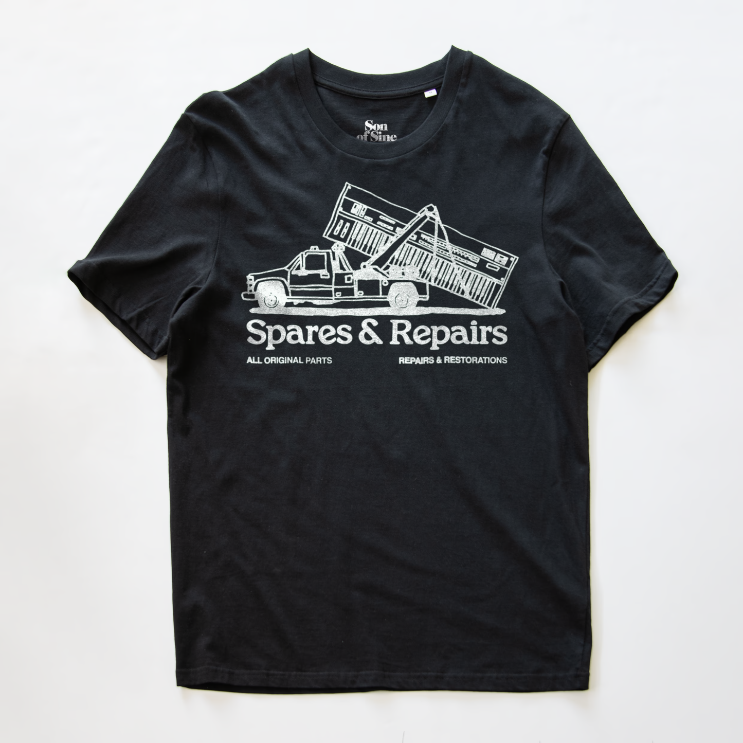 A black synth t-shirt with a white graphic print of a dump truck towing a synth and the text 'Spares & Repairs' on the front.