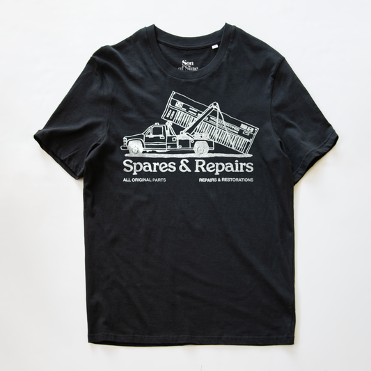 A black synth t-shirt with a white graphic print of a dump truck towing a synth and the text 'Spares & Repairs' on the front.