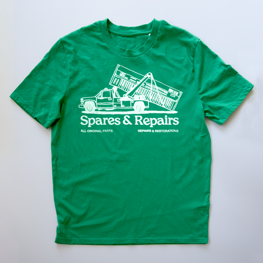 A green short-sleeve t-shirt with a white graphic print of a tow truck and the text 'Spares & Repairs' on a light gray background.