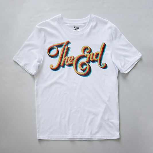 A white electronic music festival t-shirt with a retro-style graphic reading 'The End' in a wavy, layered 3D font with red, orange, and blue shadow effects.