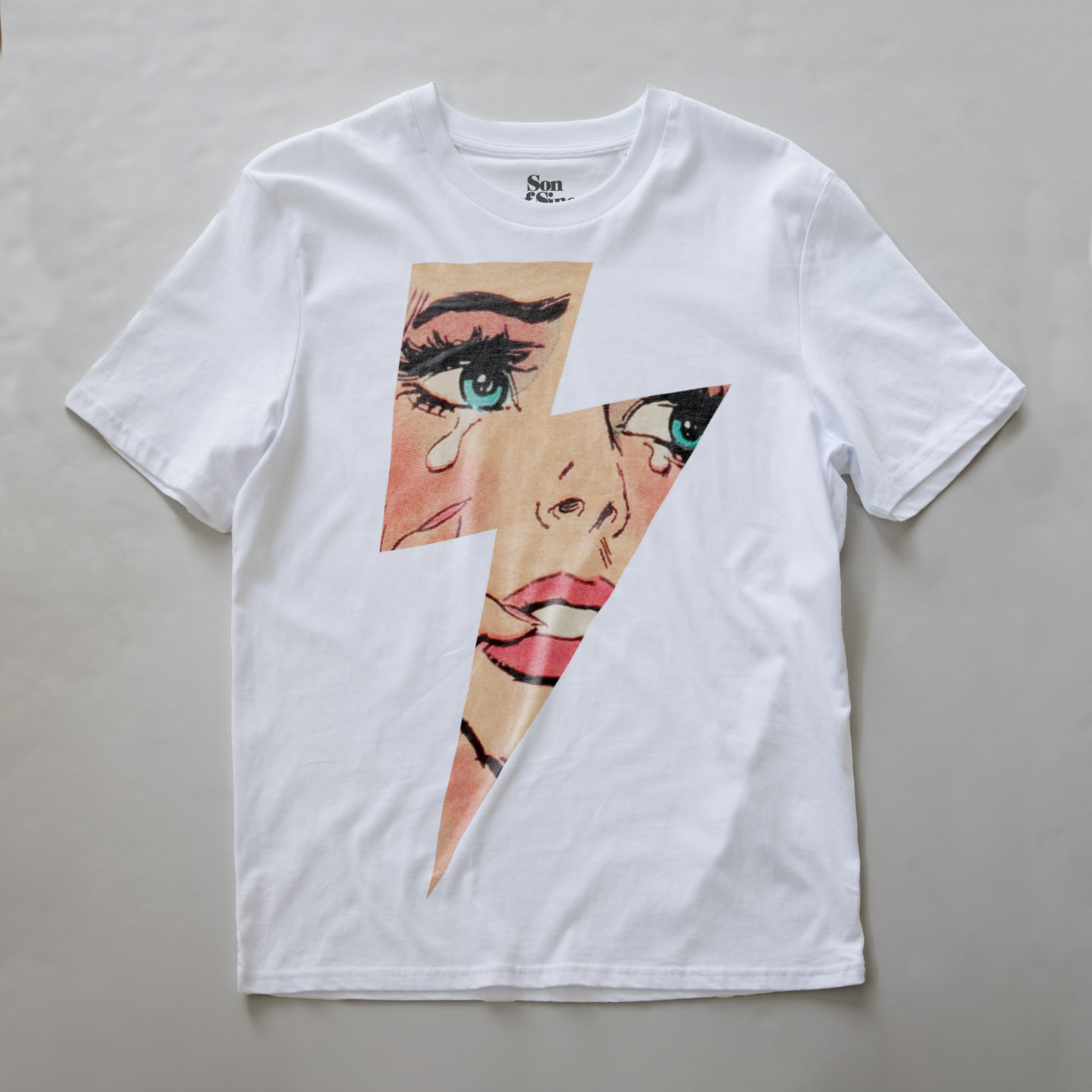 A white electronic music t-shirt with a graphic print of a lightning bolt revealing a comic book styled image of a crying woman's face. 