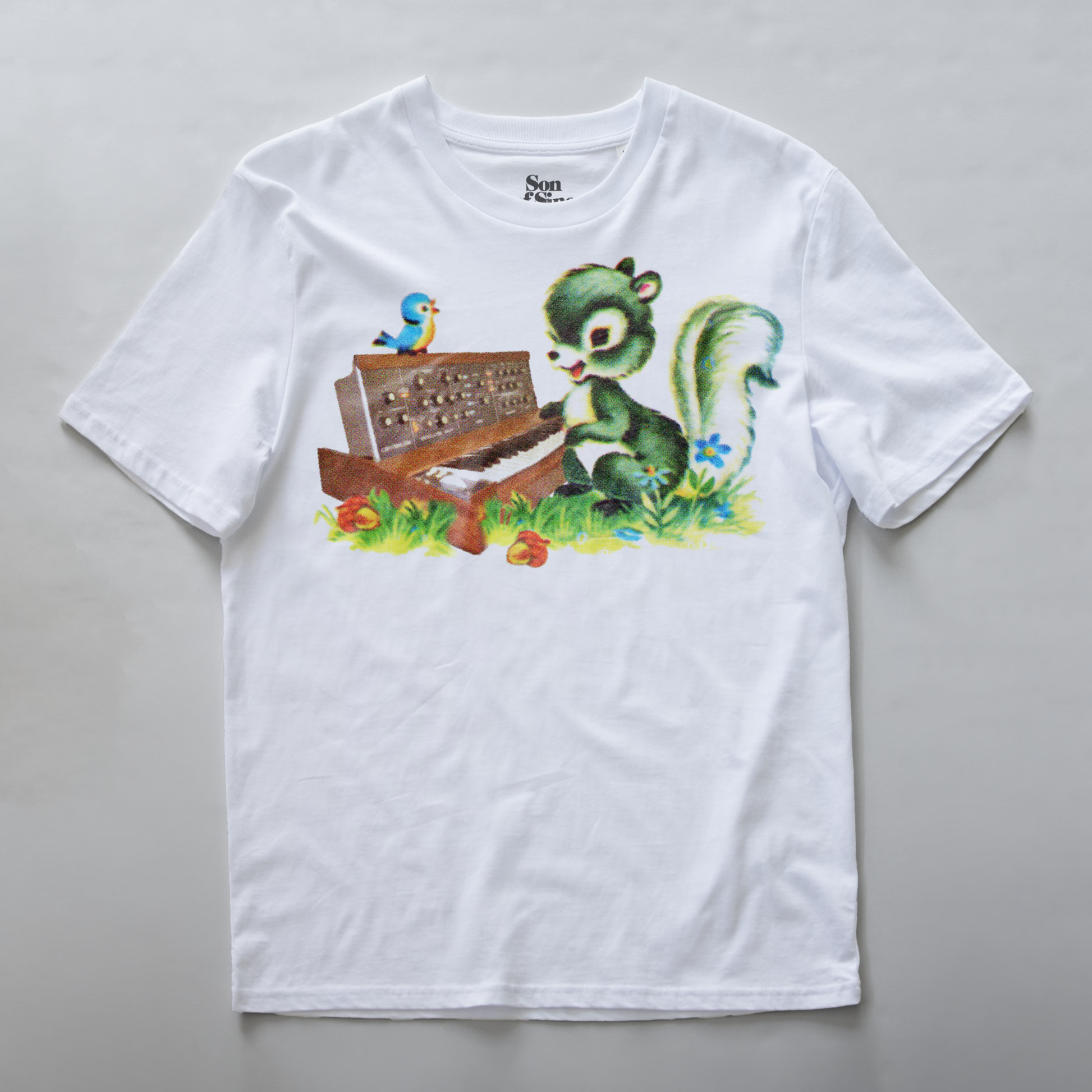 A white synth t-shirt with a colorful graphic print of a green squirrel playing a brown vintage minimoog model D synth on a grassy patch, with a small blue bird perched on top.