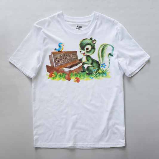 A white synth t-shirt with a colorful graphic print of a green squirrel playing a brown vintage minimoog model D synth on a grassy patch, with a small blue bird perched on top.